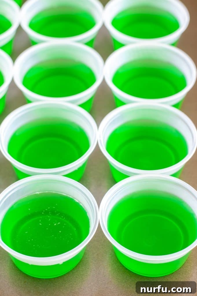 Ultimate Tequila JELL-O Shots 5 A baking dish filled with small cups of green JELLO shots, chilling in the refrigerator.