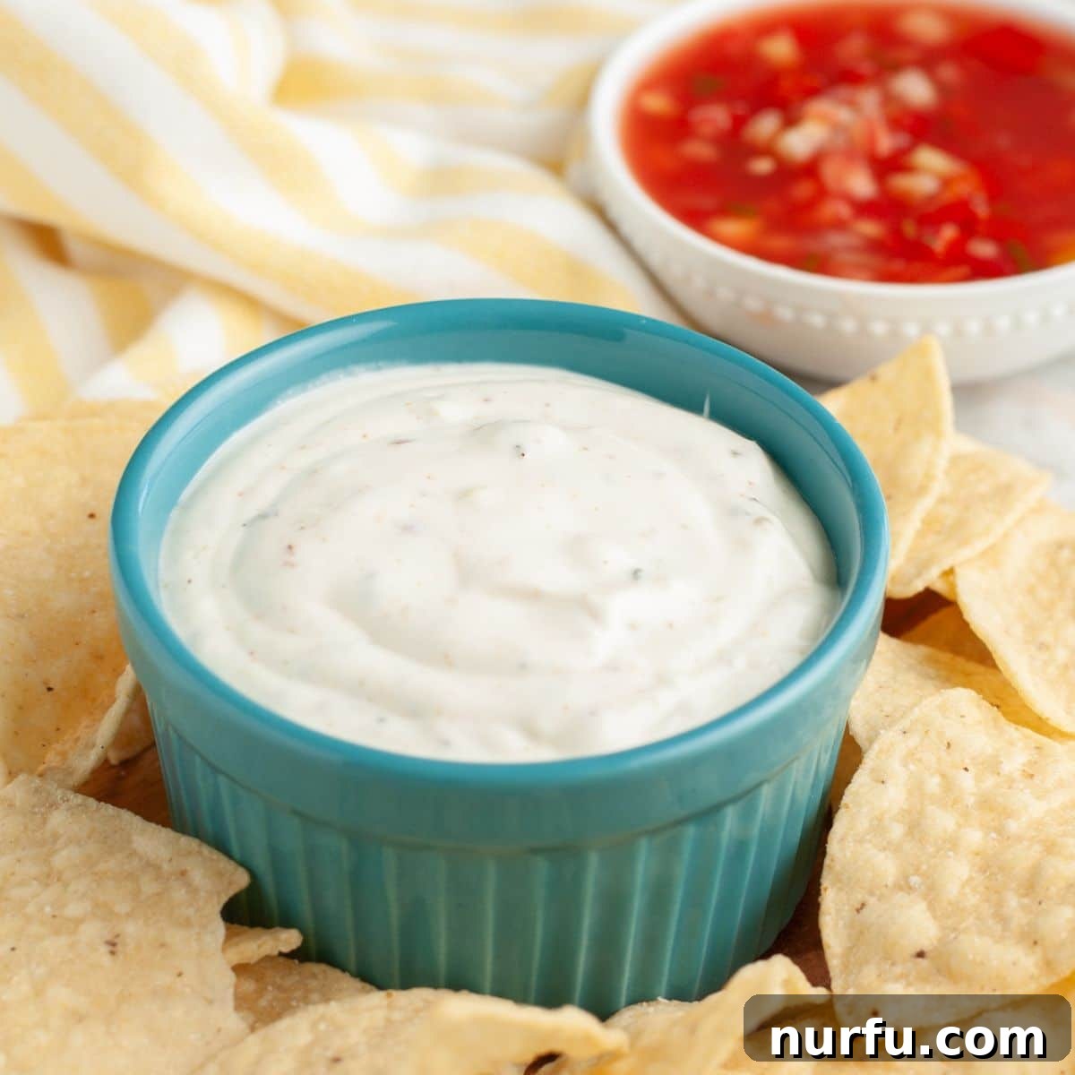 Creamy Mexican Restaurant White Sauce 6 An appetizing spread featuring a bowl of creamy white sauce, a bowl of vibrant red salsa, and a pile of crispy tortilla chips, ready for dipping.