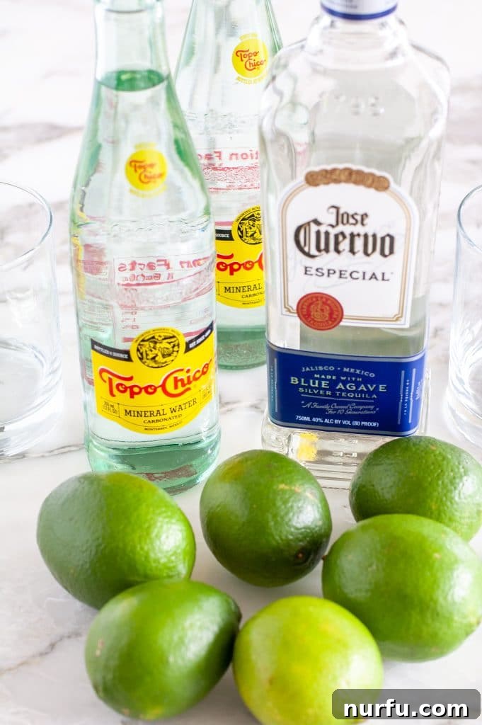 The essential ingredients for Ranch Water: a bottle of Topo Chico, a bottle of clear tequila, and several fresh green limes, ready for mixing.