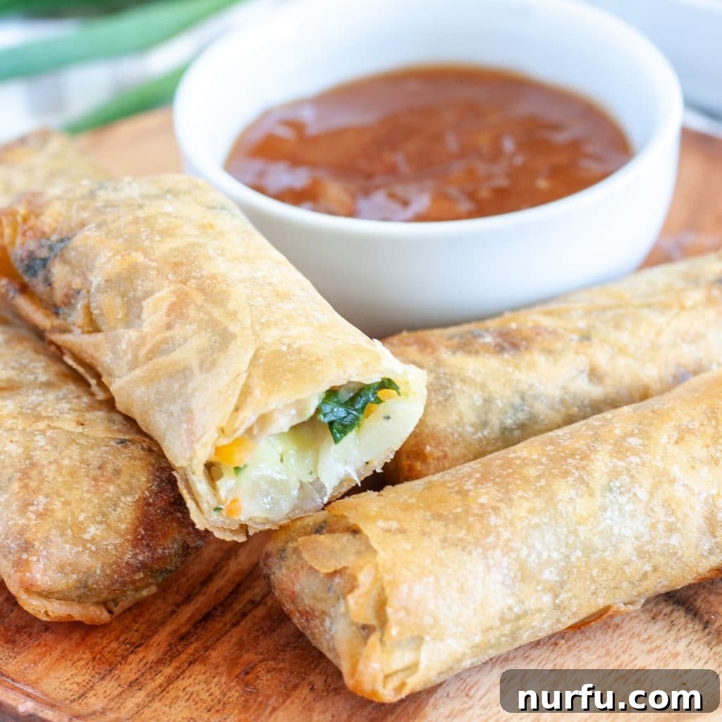 Crispy Air-Fried Frozen Spring Rolls 2 Stacked crispy spring rolls on a white plate, ready to be served as an appetizer.