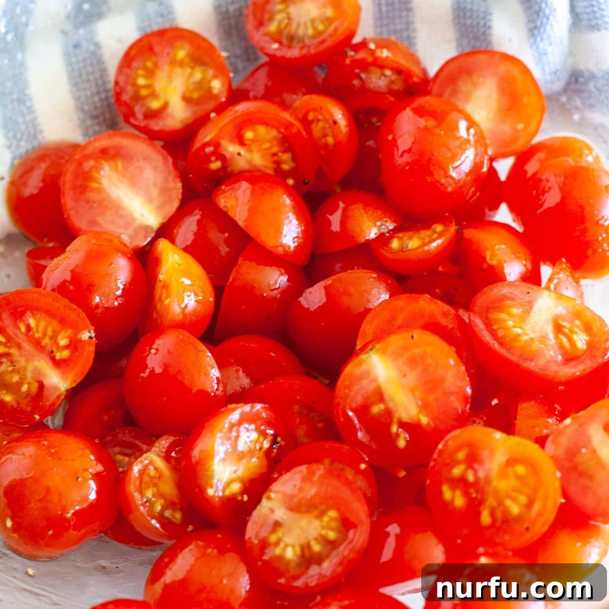 Air Fried Tomato Bites 4 A bowl filled with fresh, halved cherry tomatoes, glistening slightly with olive oil and seasonings, ready for the air fryer.