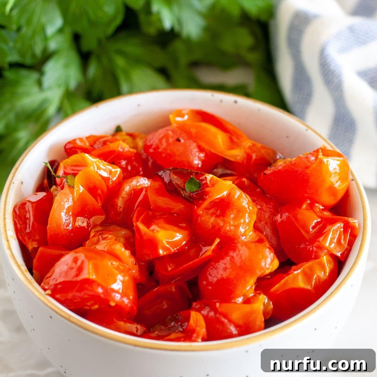 Air Fried Tomato Bites 6 A rustic ceramic bowl brimming with freshly roasted tomatoes, some still retaining their rounded shape while others are slightly collapsed, all bursting with color.