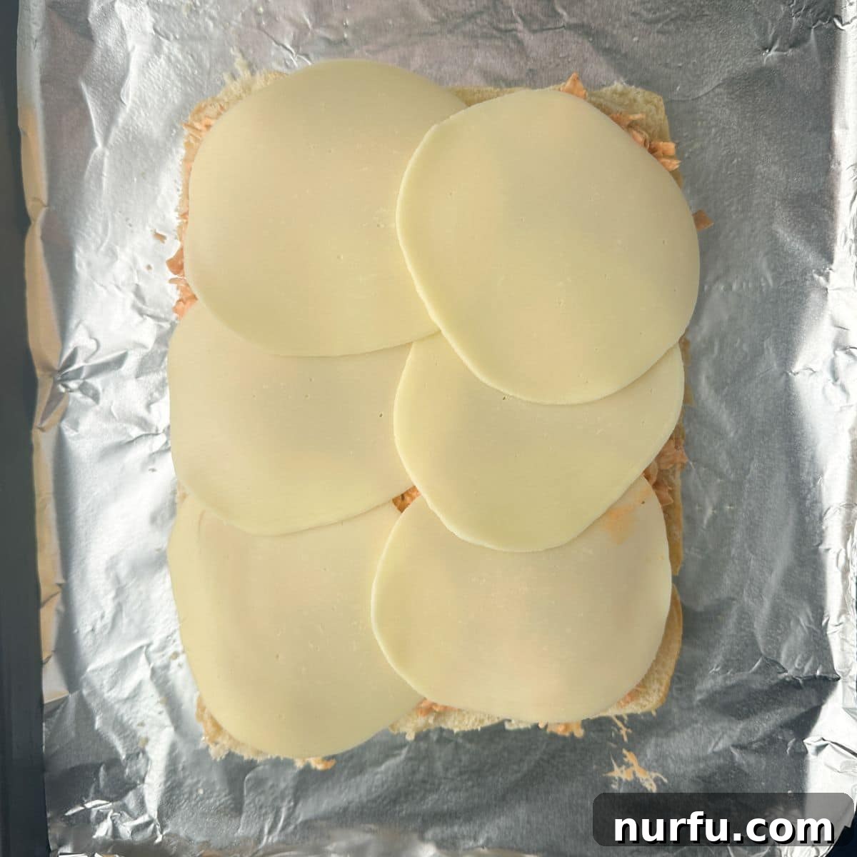 Slices of provolone cheese layered over the buffalo chicken filling on Hawaiian rolls.