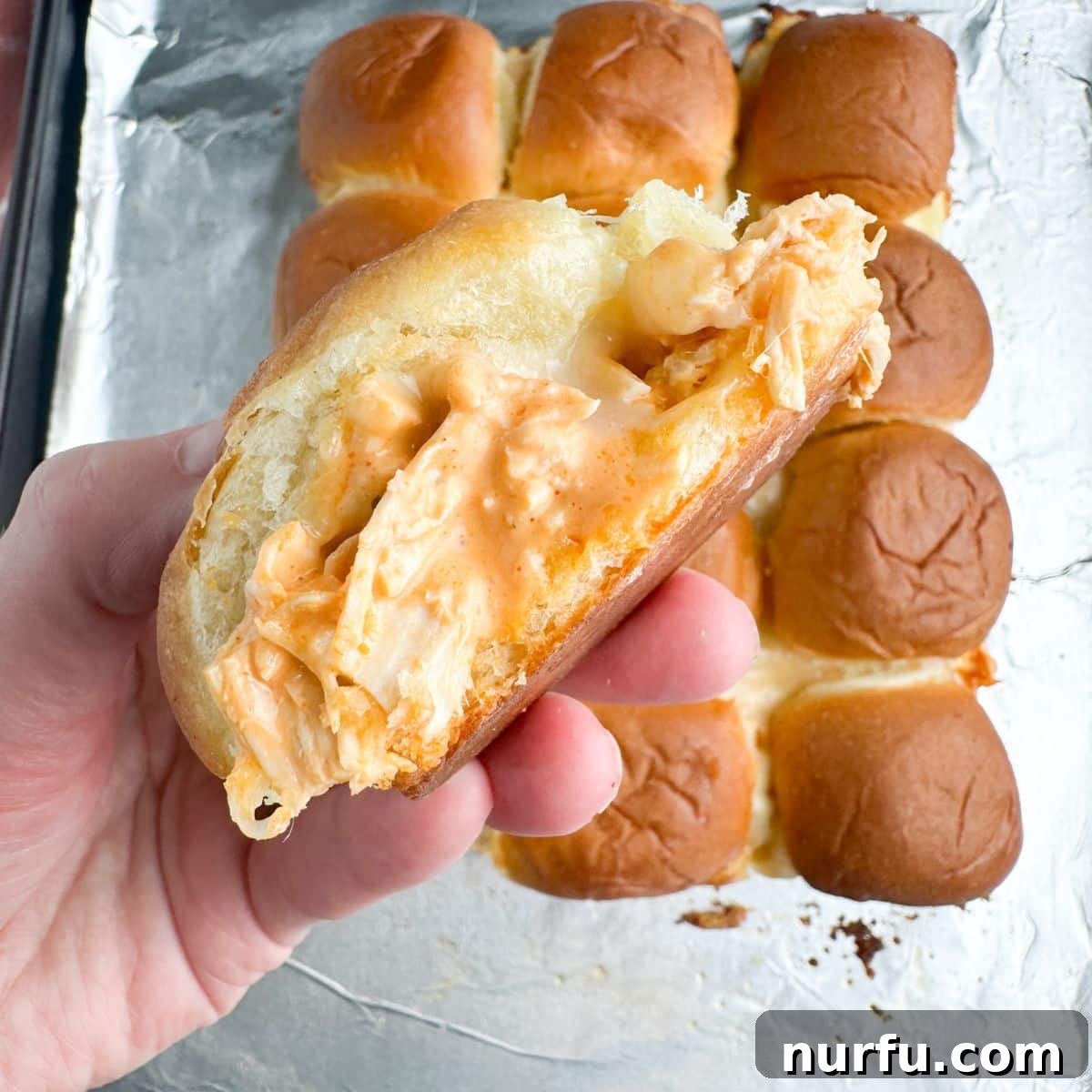 A freshly baked pan of buffalo ranch chicken sliders, glistening with melted cheese and golden-brown tops, ready to be served.