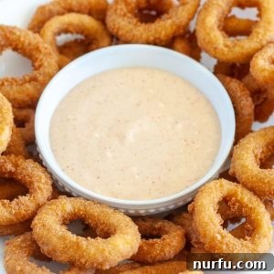 Burger King Signature Zesty Dip 7 A bowl of creamy Zesty Sauce surrounded by crispy onion rings, ready to be enjoyed.