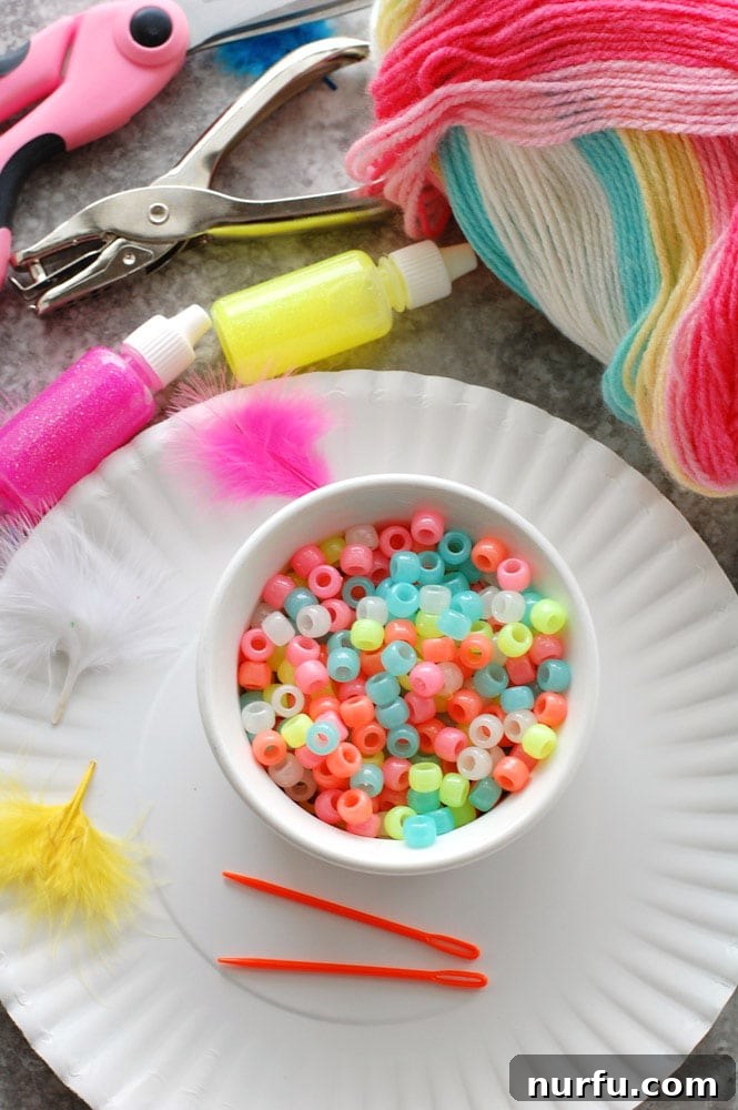 A vibrant collection of DIY dream catcher craft supplies laid out on a table, including a bowl of colorful beads, tubes of glitter glue, and various spools of yarn, ready for a creative kids' crafting session.