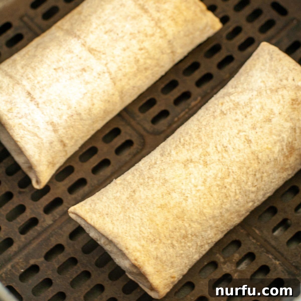 Crispy Air Fryer Frozen Burritos 4 Frozen burritos carefully arranged in a single layer within an air fryer basket, ready for cooking.