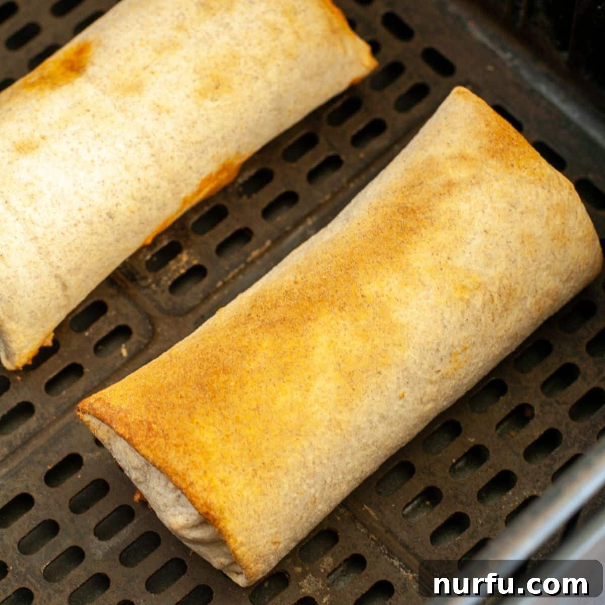 Crispy Air Fryer Frozen Burritos 5 Perfectly cooked, golden-brown frozen burritos resting in an air fryer basket after cooking.