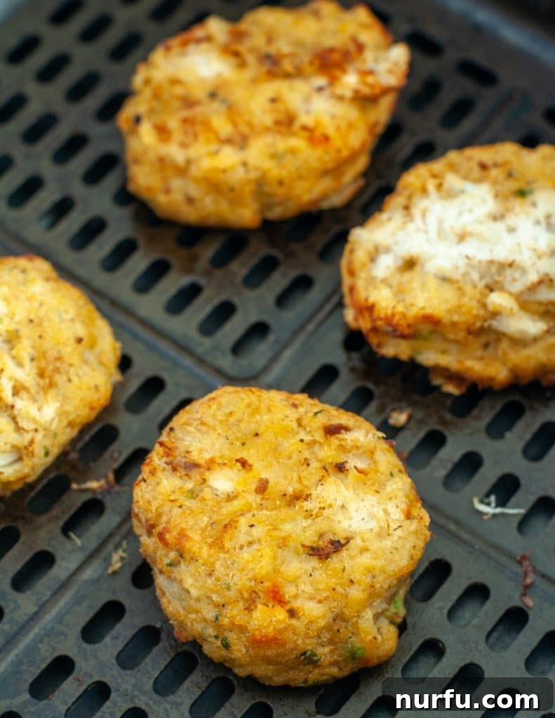 Crispy Air Fryer Frozen Crab Cakes 4 Freshly cooked, golden-brown crab cakes resting in an air fryer basket, illustrating their perfect crispness and readiness to serve.