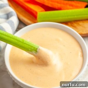 Bowl of dip with a celery stick.
