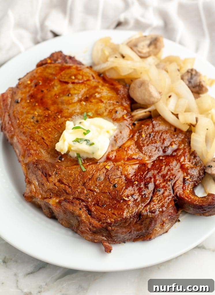 Air Fryer Ribeye Perfection 2 Steak on a plate topped with butter.