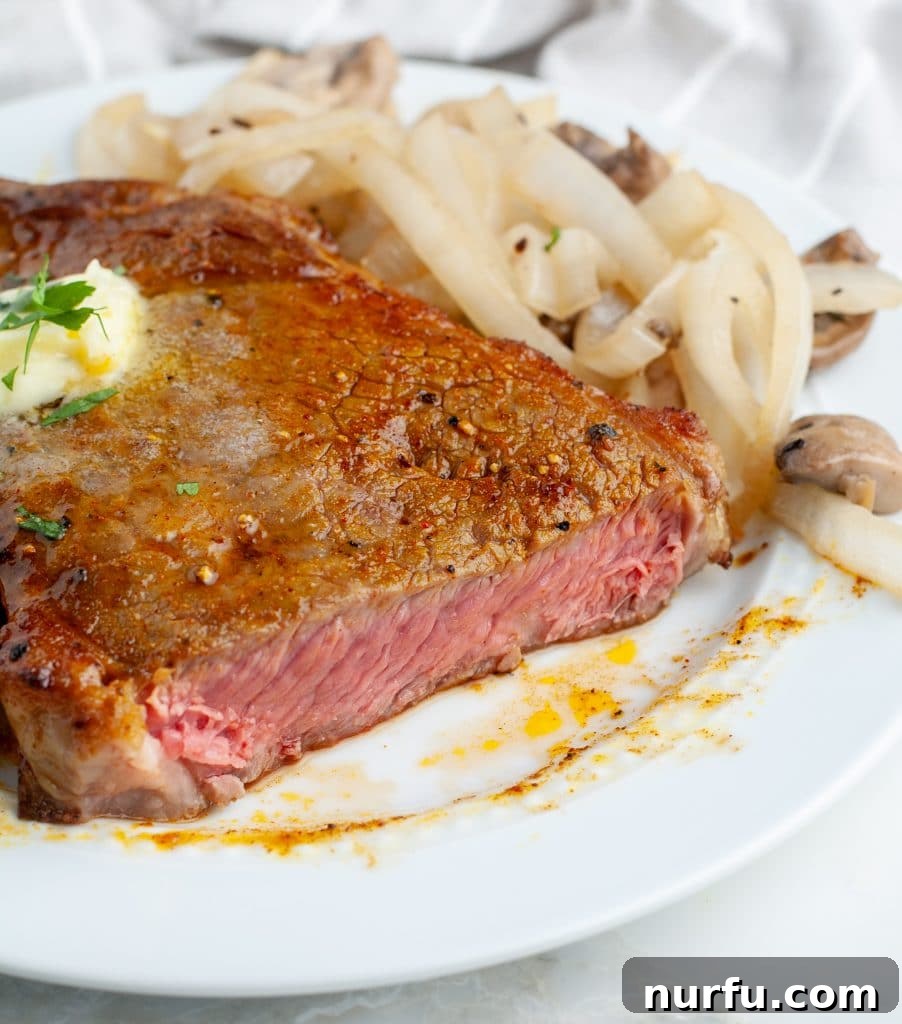 Air Fryer Ribeye Perfection 4 Cut steak on a plate with onions and mushrooms.
