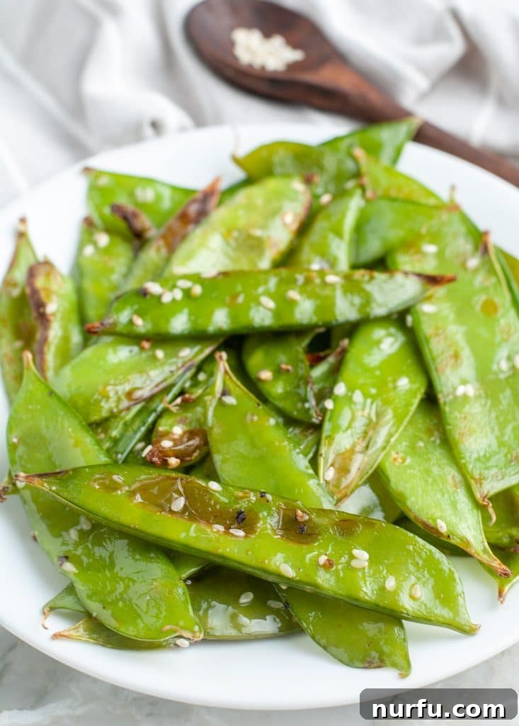 Golden Crisp Air Fryer Snow and Snap Peas 2 Crisp air-fried snow peas seasoned with sesame seeds, presented beautifully on a plate.