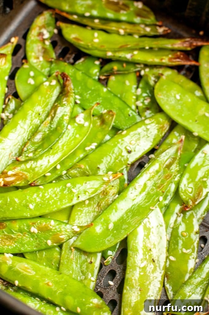 Golden Crisp Air Fryer Snow and Snap Peas 5 Cooked air-fried snow peas resting in an air fryer basket, showcasing their perfectly roasted appearance.