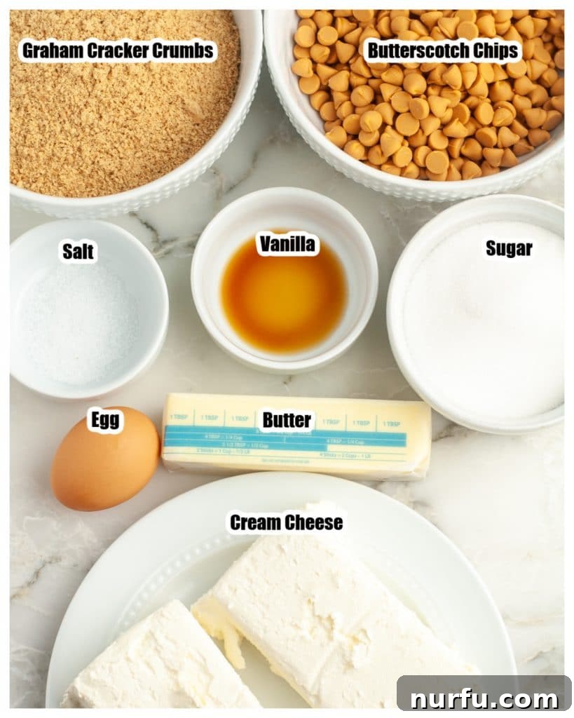 Decadent Butterscotch Cheesecake Squares 3 A collection of ingredients laid out: bowl of graham cracker crumbs, butterscotch chips, sugar, butter, cream cheese block, and an egg.
