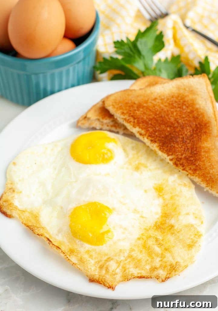 Golden & Crispy Air Fryer Fried Eggs 2 Two perfectly cooked fried eggs on a plate, ready to be served.