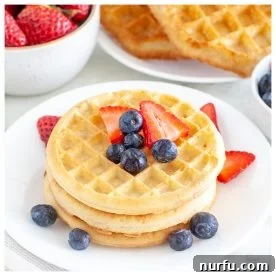 A tall stack of golden frozen waffles, garnished with fresh berries and ready to serve.