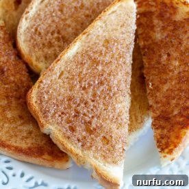Golden cinnamon toast slices resting on a plate, perfectly browned and sprinkled with spice.