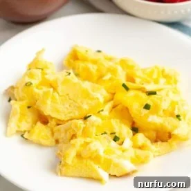 Fluffy scrambled eggs perfectly cooked and served on a plate.
