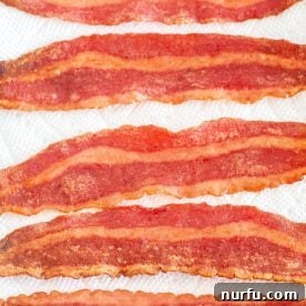 Crispy turkey bacon slices draining on a paper towel after being cooked to perfection.