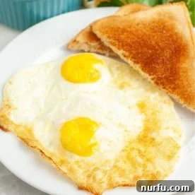 Perfectly cooked fried eggs served on a plate with crispy toast.
