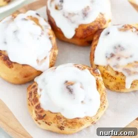 Warm, glazed cinnamon rolls artfully arranged on a plate.