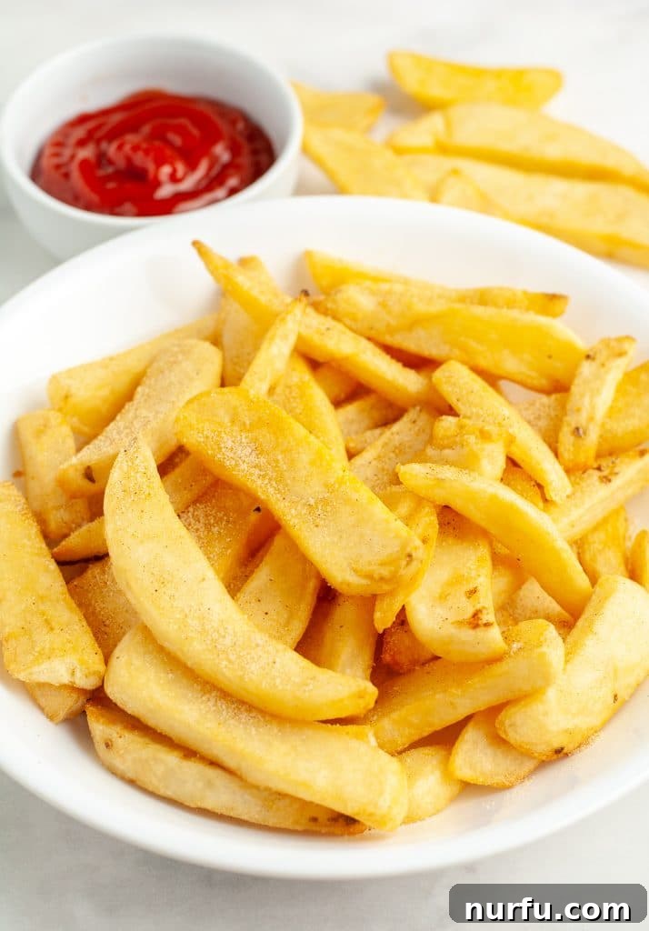 A bowl brimming with golden-brown, perfectly cooked steak fries, garnished with fresh herbs and ready to be enjoyed.