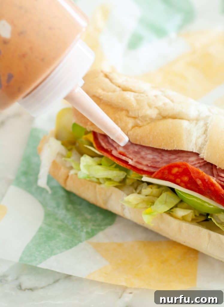 Crack the Code: Subway's Chipotle Sauce Recipe 4 A freshly made sandwich drizzled with homemade Subway Chipotle Southwest Sauce, served alongside a bottle of the sauce for easy access.