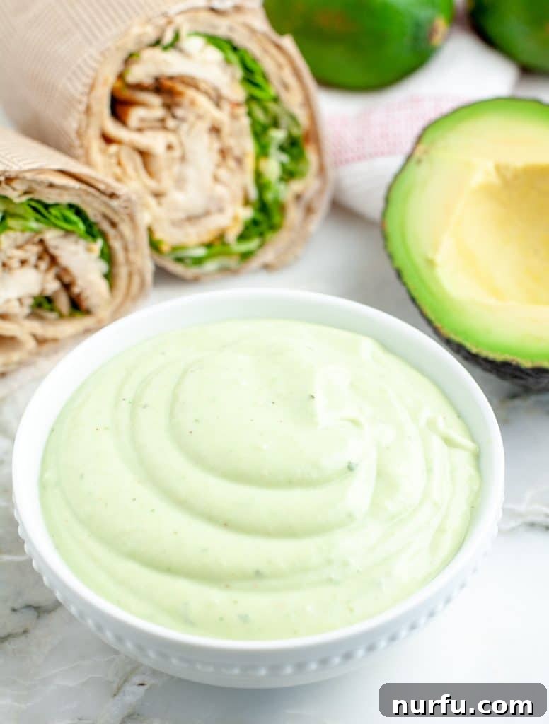 Recreate Chick-fil-A's Famous Avocado Lime Ranch Dressing 2 Bowl of vibrant green avocado lime ranch dressing with half an avocado beside it.