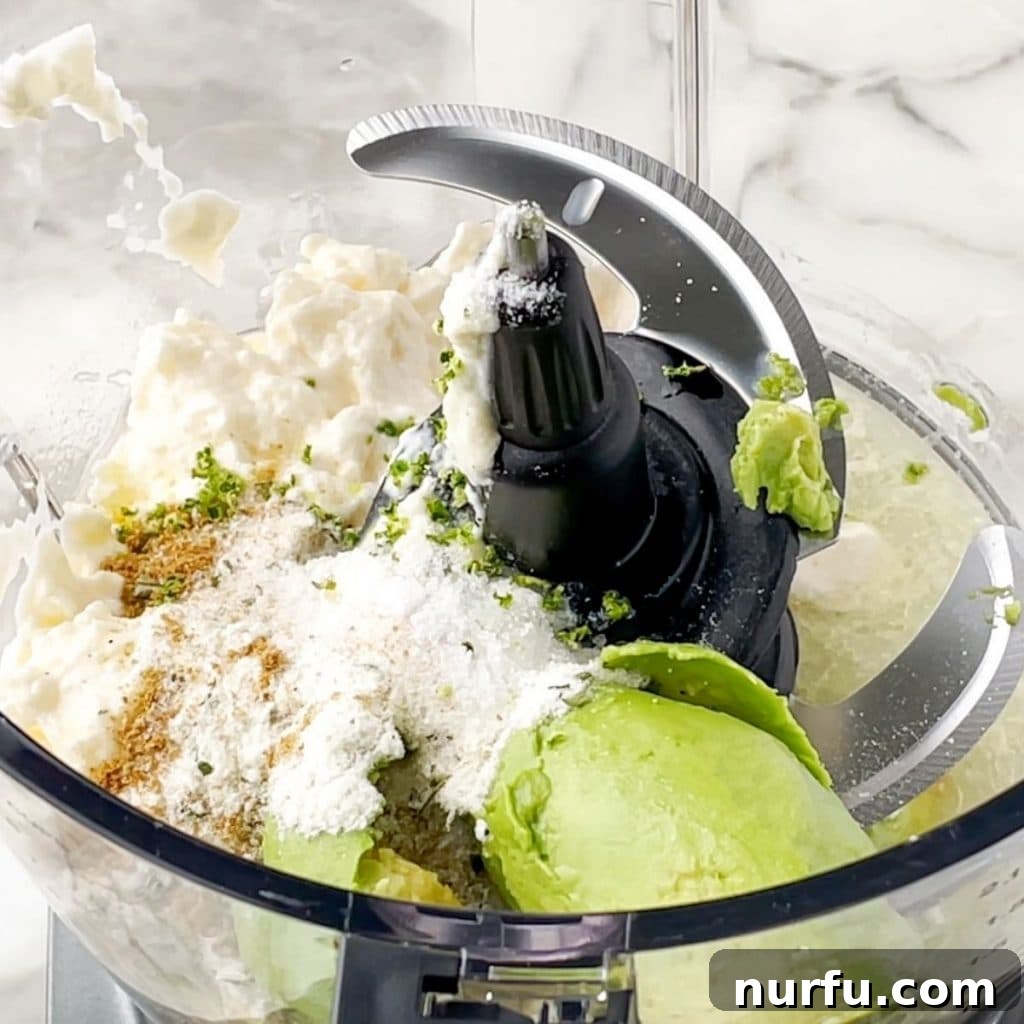 Recreate Chick-fil-A's Famous Avocado Lime Ranch Dressing 4 Food processor containing blended avocado, mayonnaise, and spices, showing the creamy texture.