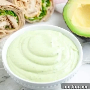 Green dressing in a bowl with chicken wrap.