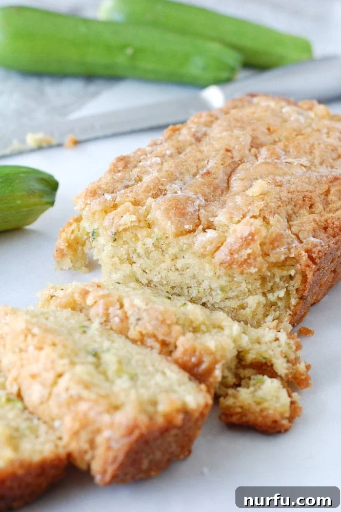 A perfectly sliced loaf of zucchini bread, revealing its moist and tender crumb, resting on a cutting board.