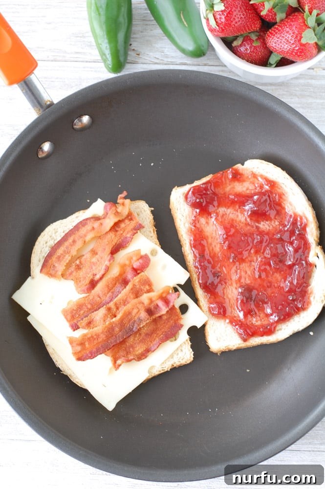 Strawberry Jalapeno Bacon Melt 5 Preparing the grilled cheese: a slice of sourdough bread generously spread with strawberry jalapeno fruit spread, next to another slice topped with Swiss cheese and bacon.