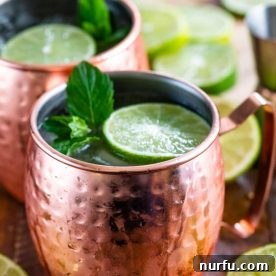 A classic Moscow Mule served in a shiny copper cup, garnished with a lime wedge, ready to be enjoyed.