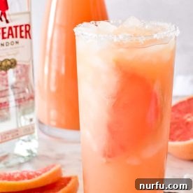 A vibrant pink Salty Dog drink served in a tall glass, with a salted rim for extra flavor.