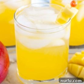 Two glasses of a vibrant mango vodka cocktail, garnished with fresh diced mango pieces.