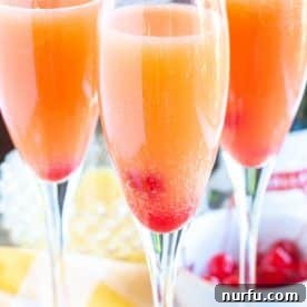 Glasses filled with effervescent mimosas, garnished with vibrant cherries, creating an inviting visual.