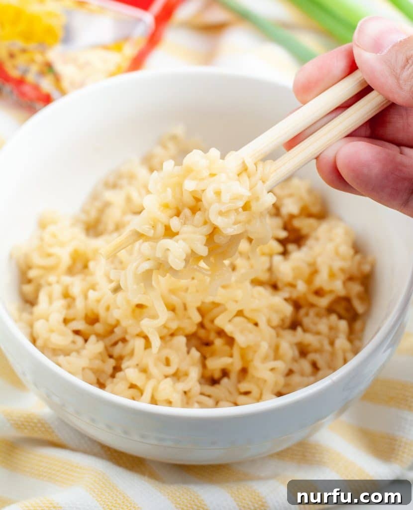 Perfecting Microwave Ramen 4 Chopsticks lifting perfectly cooked ramen noodles from a bowl, highlighting the texture and readiness for eating.