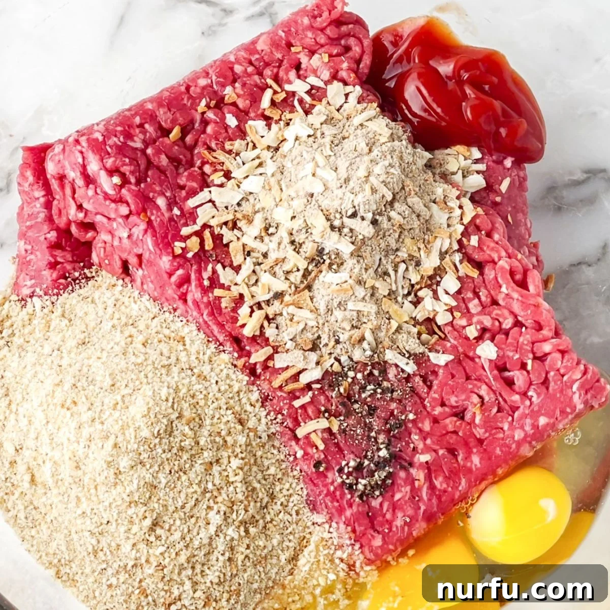 Savory Lipton Onion Soup Meatloaf 4 A bowl of ground beef is mixed with dry Lipton onion soup mix, bread crumbs, and eggs, ready to be combined for a flavorful meatloaf.
