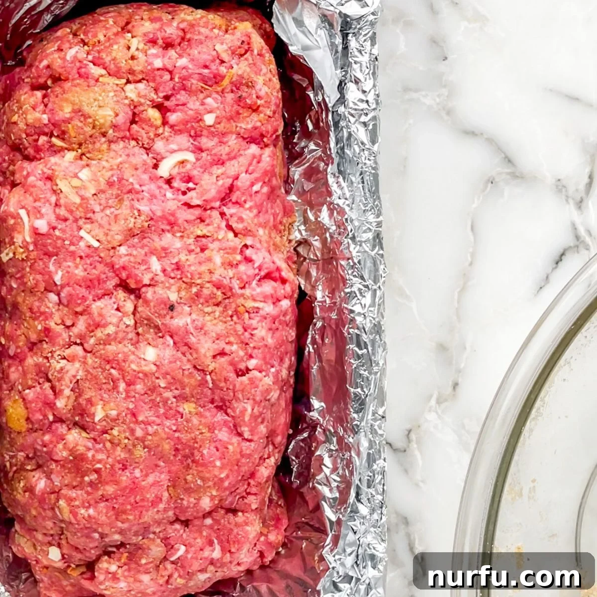 Savory Lipton Onion Soup Meatloaf 6 An uncooked Lipton Onion Soup Meatloaf, perfectly shaped and placed in a baking pan, ready for the oven to transform it into a delicious meal.