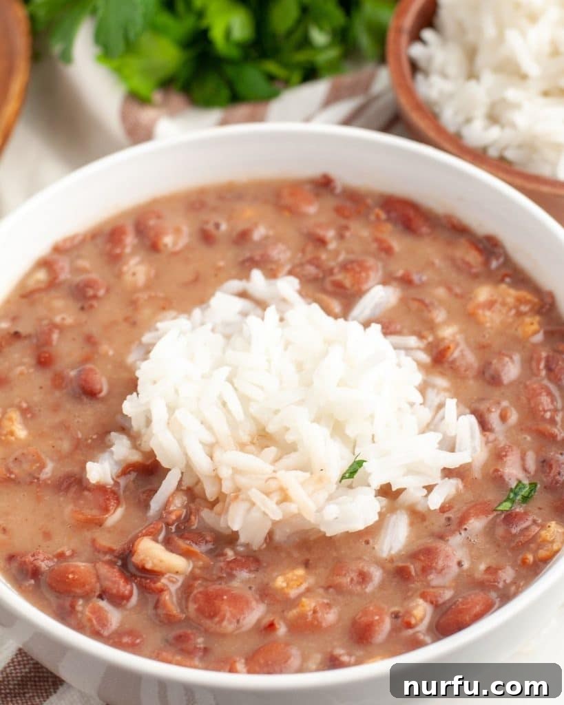 Restaurant-Style Popeyes Red Beans and Rice At Home 2 A bowl of creamy, smoky red beans topped with fluffy white rice, ready to be served.