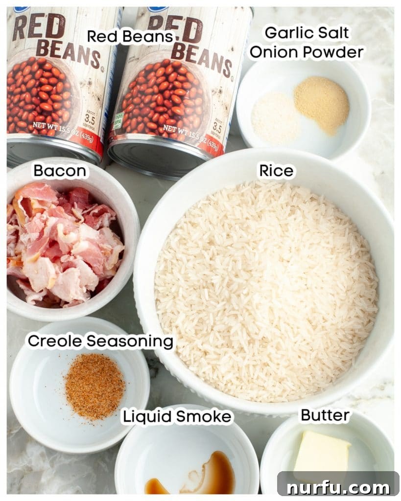 Restaurant-Style Popeyes Red Beans and Rice At Home 3 A flat lay image showing uncooked rice, various seasonings, canned red beans, raw bacon strips, and a cube of butter, arranged on a surface.