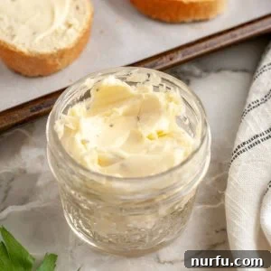 A jar of freshly made garlic butter spread, with slices of golden brown toast resting beside it, highlighting its perfect texture and inviting aroma.