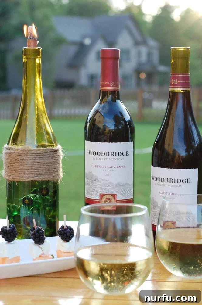 Two beautiful DIY wine bottle tiki torches on an outdoor table, ready for a backyard party.