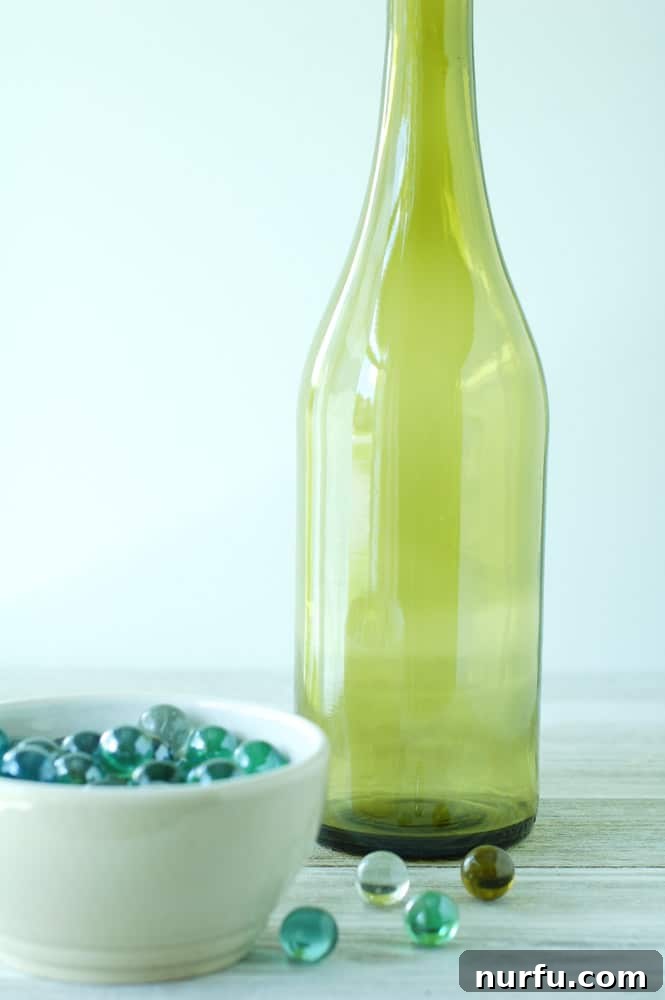 A wine bottle being wrapped with jute twine using a hot glue gun, demonstrating the optional decorative step.