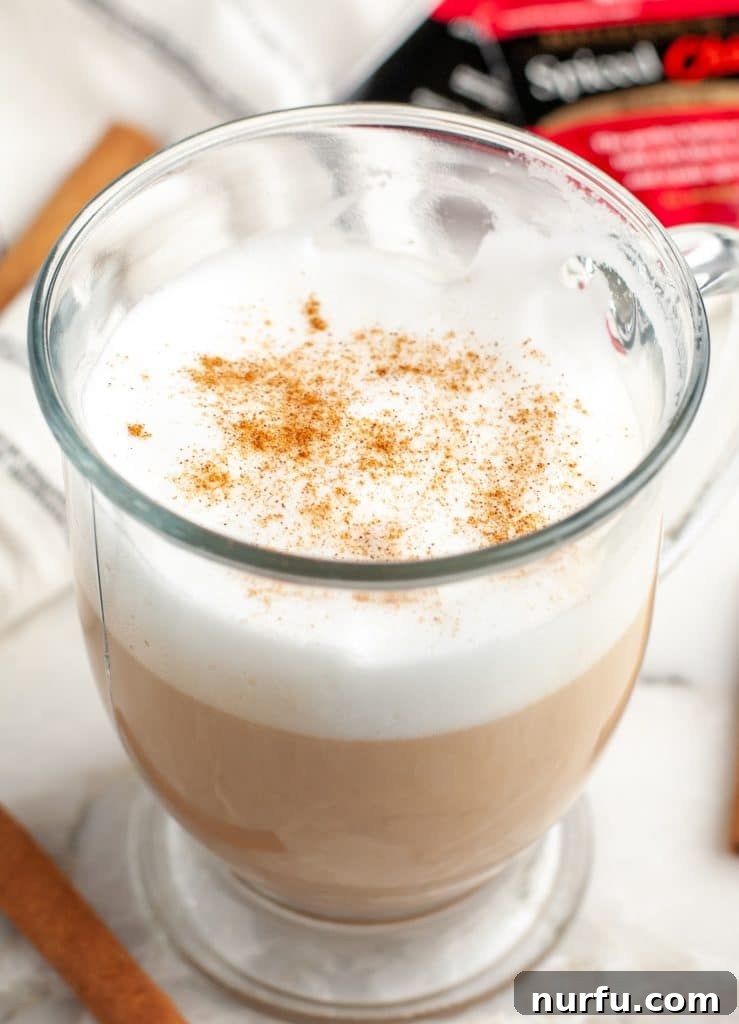 Whip Up Starbucks Chai At Home 2 A freshly made, steaming hot chai tea latte in a mug, garnished with a sprinkle of cinnamon.