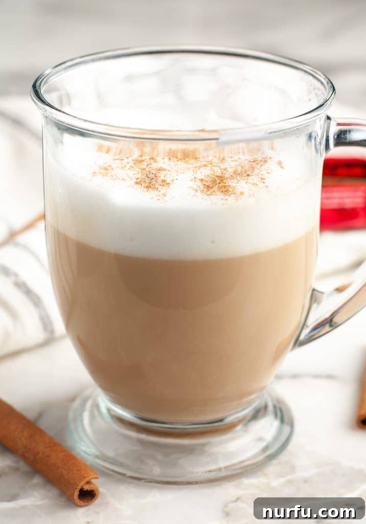 Whip Up Starbucks Chai At Home 6 A cozy coffee mug filled with a rich, frothed chai tea latte, resting on a wooden surface.