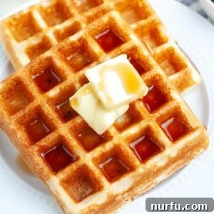Plate of golden Bisquick waffles with a pat of melting butter on top, ready to be drizzled with syrup.