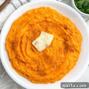 A rustic bowl of creamy whipped sweet potatoes, perfectly garnished for a comforting meal.
