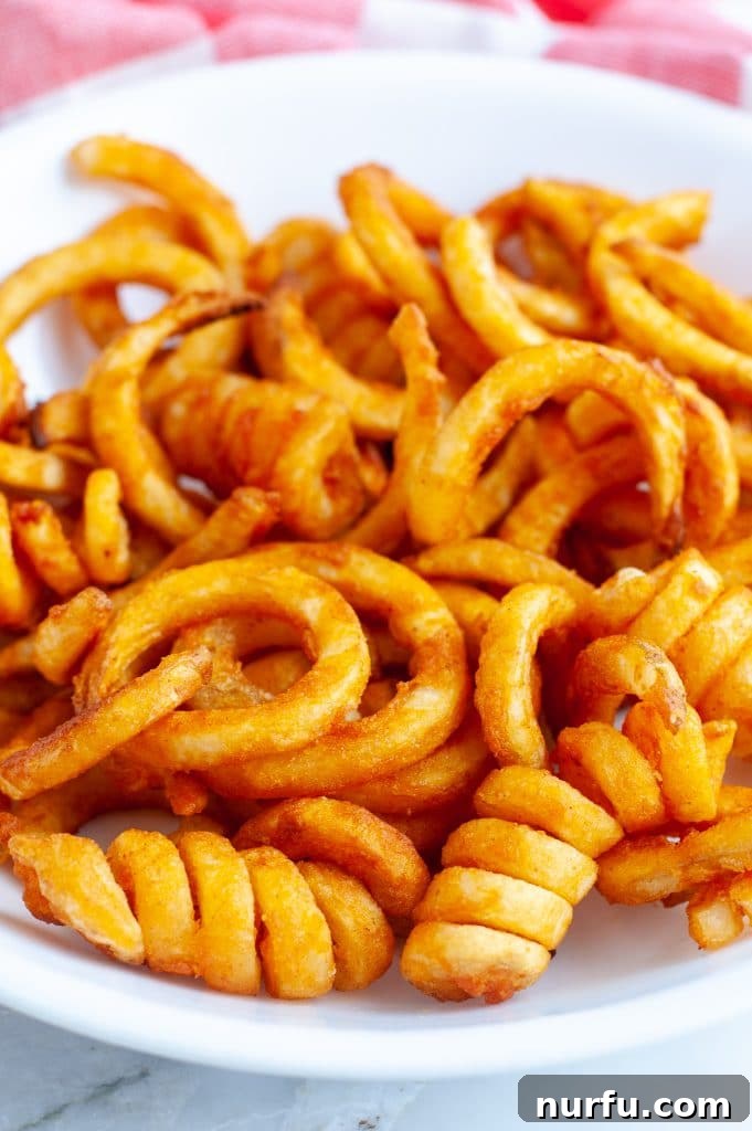 Perfectly Crispy Air Fryer Curly Fries 2 A vibrant bowl filled with golden, perfectly crispy curly French fries, ready to be enjoyed.